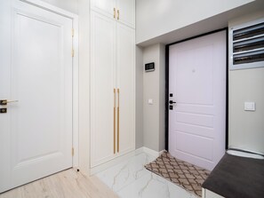 A hallway with white doors, a patterned rug, and a thermostat on the wall. - Spacious 3-room apartments (Almaty)