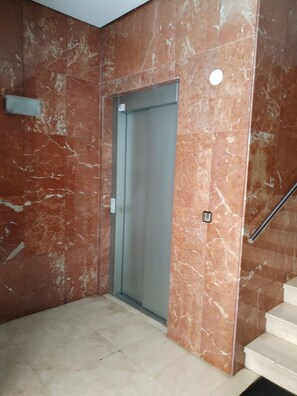 Ein Korridor mit Marmorwand, einer Tür und einer Treppe.