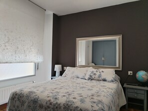 Ein Schlafzimmer mit Bett, Schminktisch, Spiegel und Globus.