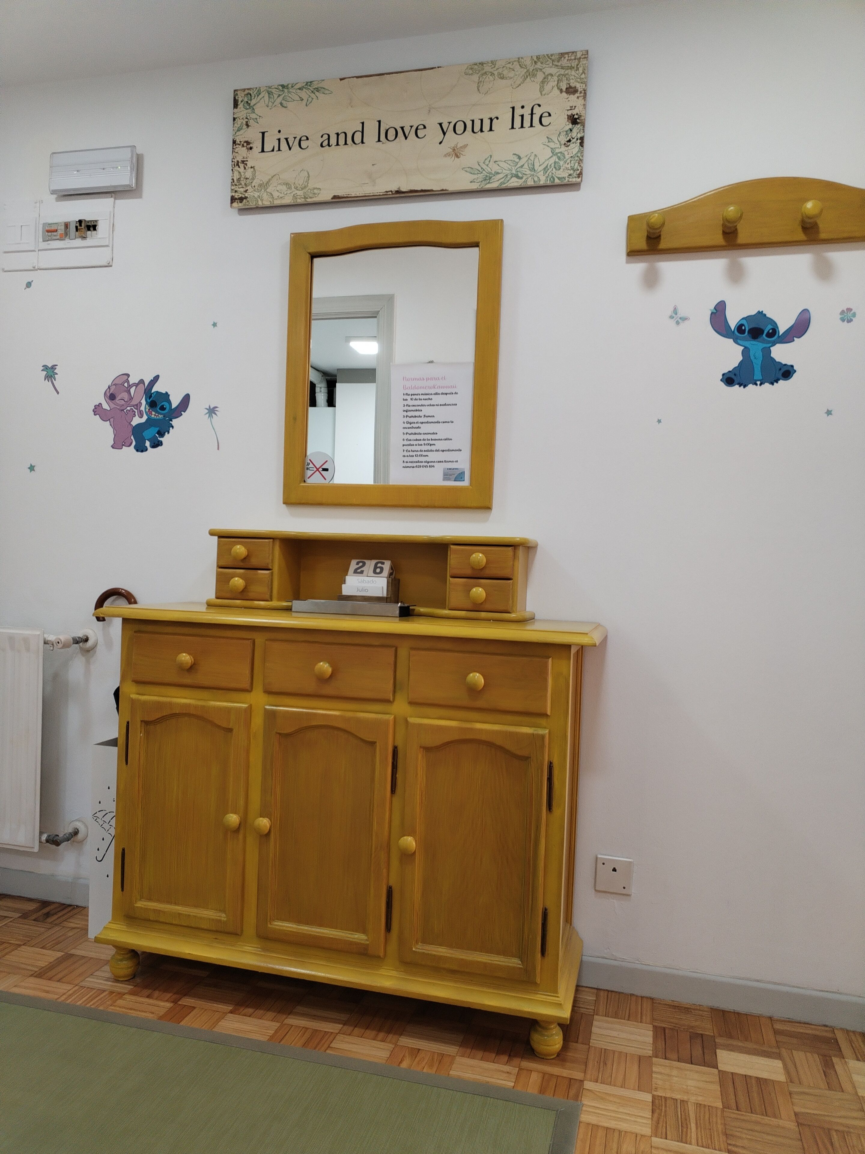 Une pièce comprenant un meuble en bois, un miroir et des éléments de décoration murale, notamment une enseigne et des personnages de dessins animés.