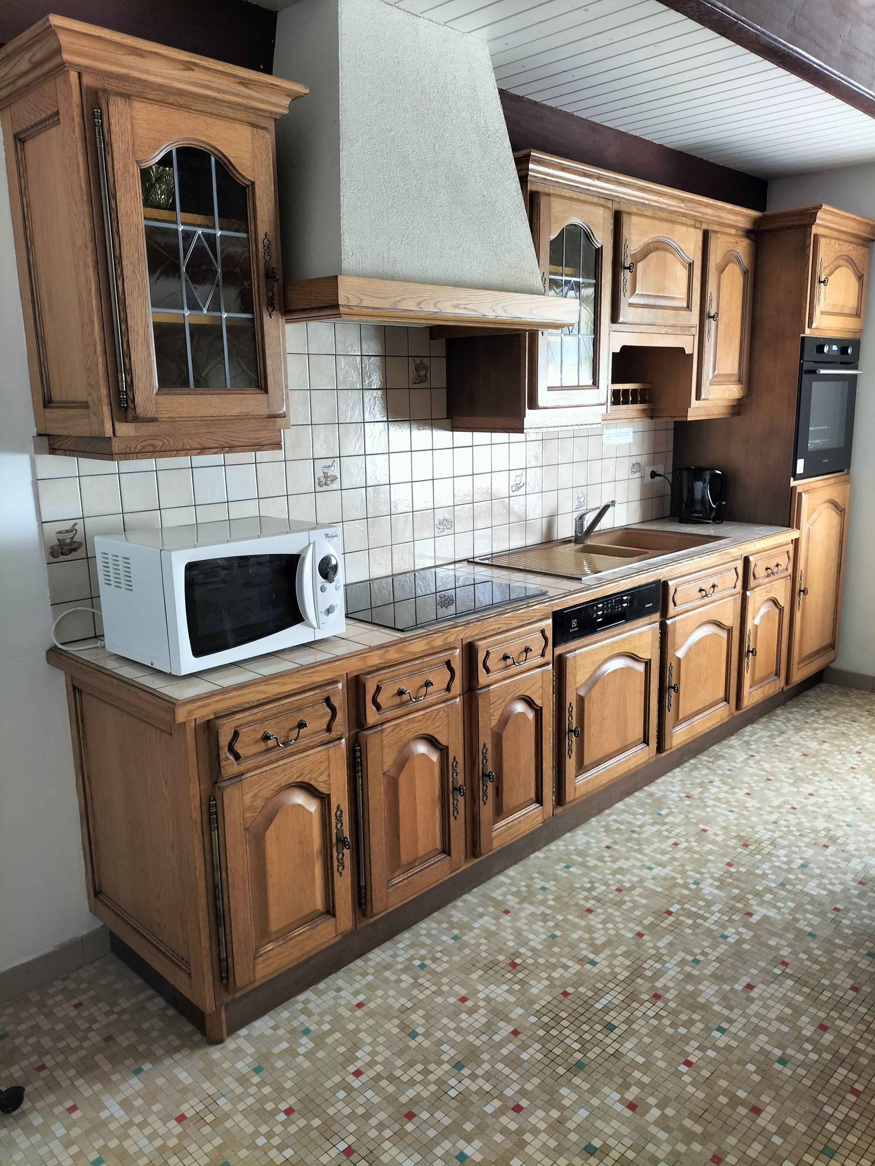 A kitchen with wooden cabinets, a microwave, a sink, and a tiled backsplash.