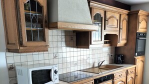 Une cuisine avec des meubles en bois, un four à micro-ondes, un évier et un dosseret carrelé.