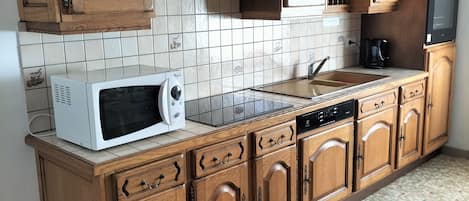 A kitchen with wooden cabinets, a microwave, a sink, and a tiled backsplash.