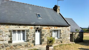 Une maison en pierre avec un toit en pente, une petite fenêtre et une porte.