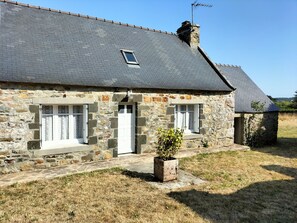 A stone house with a sloped roof, a small window, and a door.