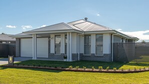 A single-story house with a garage, a covered porch, and a well-maintained lawn.