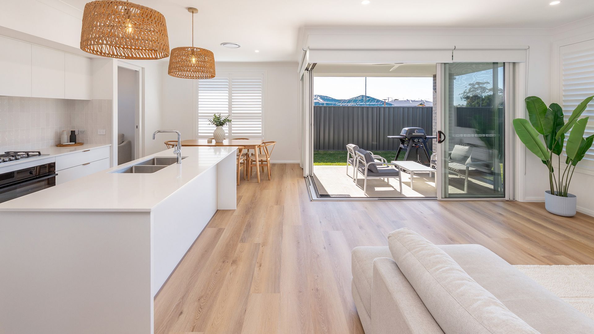 Een moderne keuken met een centraal eiland, een eetgedeelte met een tafel en stoelen, en een terras met buitenmeubels.