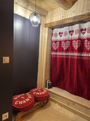 Un interior de madera con una cortina roja, una lámpara colgante y dos taburetes tapizados en rojo.