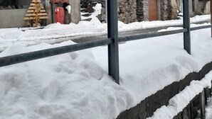 Kivestä rakennettu rakennus, jonka yläosassa on puinen rakenne, edessä metallinen kaide ja maassa lunta.