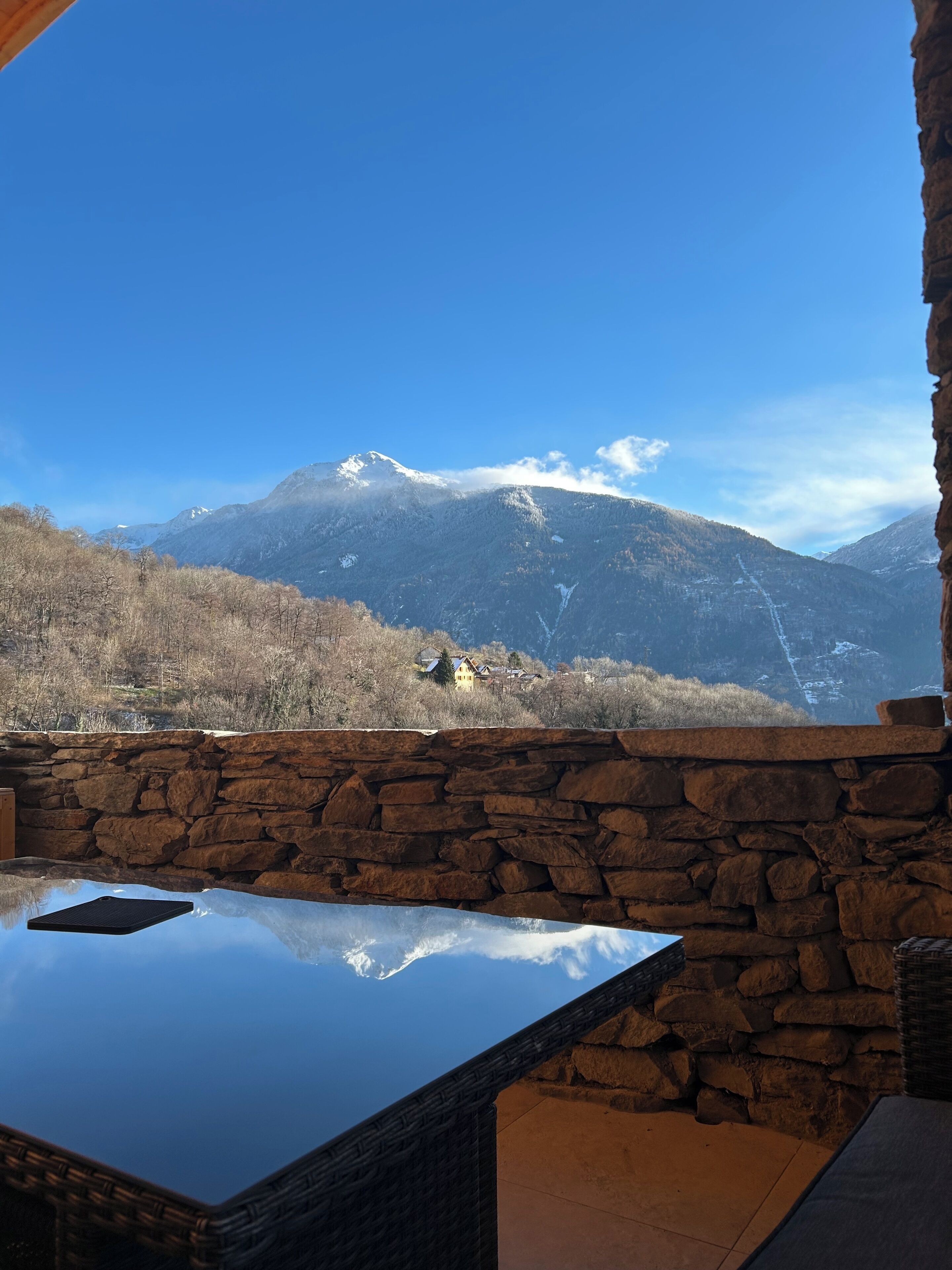 Un muro di pietra con vista su una montagna e una casa in lontananza.