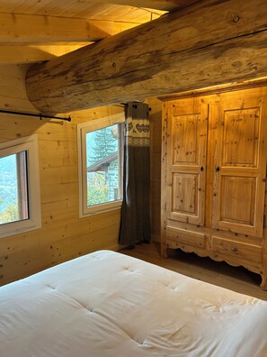 Una habitación de cabaña de madera con cama, ventana y armario.