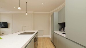 A modern kitchen with a marble countertop, built-in appliances, and pendant lighting. - Stylish Apartment on Castle Street (Edinburgh)