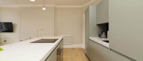 A modern kitchen with a marble countertop, built-in appliances, and pendant lighting.