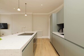 A modern kitchen with a marble countertop, built-in appliances, and pendant lighting. - Stylish Apartment on Castle Street (Edinburgh)