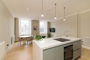 A modern kitchen with a marble countertop, built-in oven, and pendant lighting. - Stylish Apartment on Castle Street (Edinburgh)