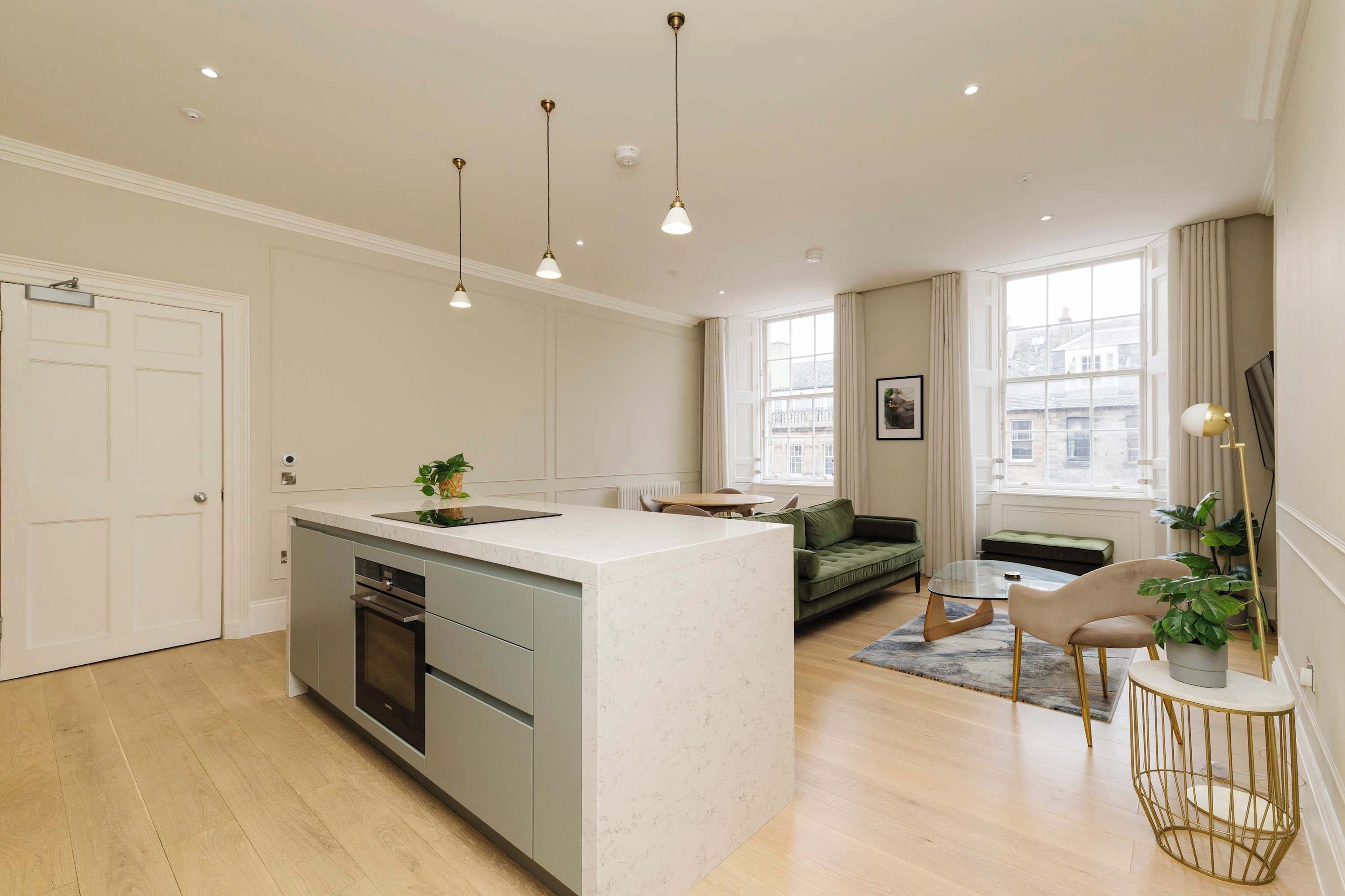 A modern kitchen with a central island, built-in appliances, and pendant lighting.