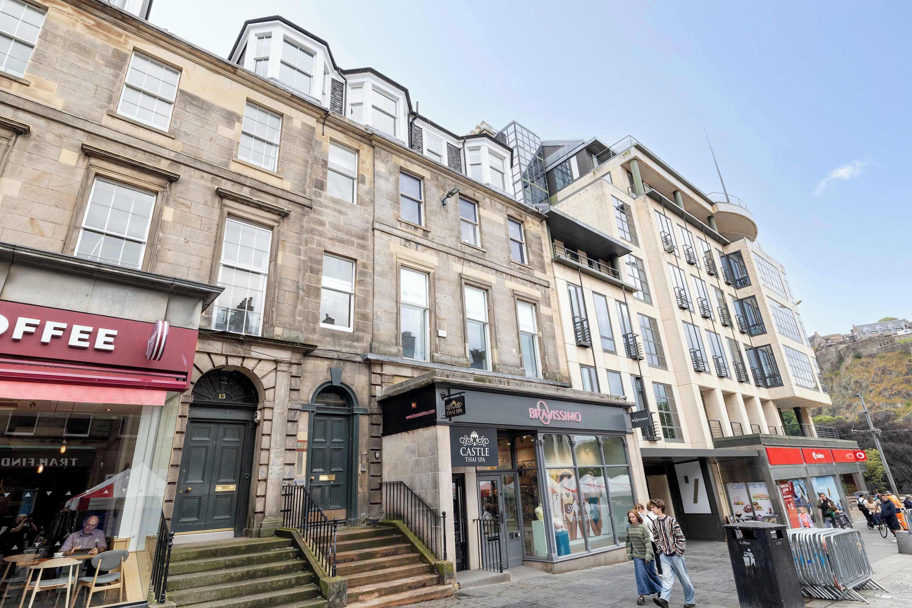 A street view with a coffee shop, a spa, and a modern building with balconies.