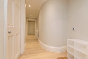 A hallway with white walls and wooden flooring, leading to a door at the end. - Stylish Apartment on Castle Street (Edinburgh)
