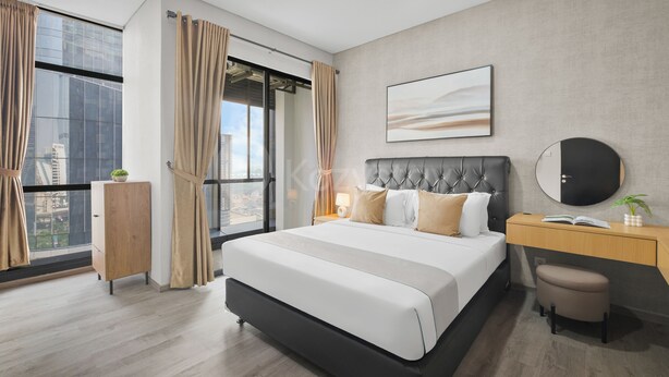 Moderni hotellihuone, jossa on suuri sänky, työpöytä ja näkymä kaupungin ylle.