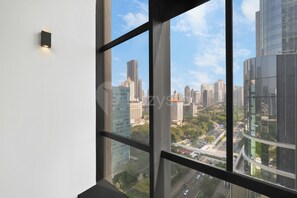 Une vue depuis une fenêtre, donnant sur un paysage urbain avec des gratte-ciel et une autoroute.