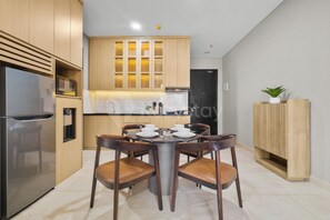 Une cuisine moderne dotée d’un réfrigérateur LG encastré, de meubles de rangement en bois, d’une table à manger avec quatre chaises et d’une petite plante en pot posée sur un meuble en bois.