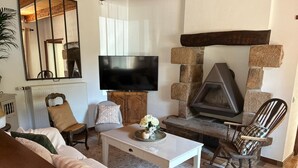 Un soggiorno con divano, poltrone, tavolino, camino e televisore.