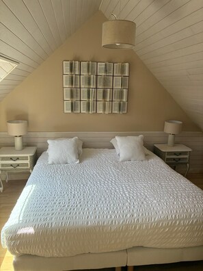 A bedroom with a large bed, two bedside tables, and a wall-mounted book display. - Le Clos du Verger: 5-Bedroom Family Home (saint quay perros)