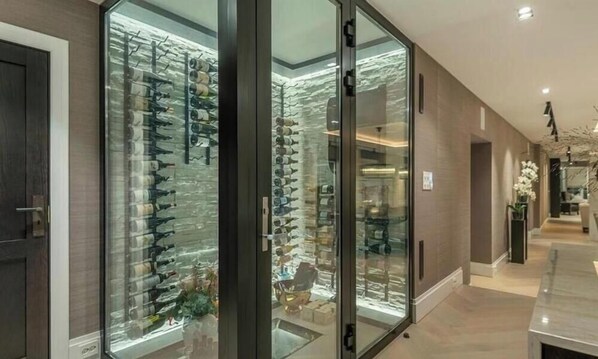 A modern interior with a glass display case filled with various items, a marble countertop, and a well-lit hallway. - Trondheim's crown jewel – an elegant luxury apartment right in the heart of downtown (Trøndelag)