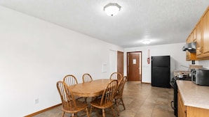 Une cuisine spacieuse avec une table et des chaises, un réfrigérateur, une cuisinière et des armoires en bois.