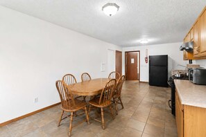 Eine geräumige Küche mit Esstisch und Stühlen, inklusive Kühlschrank, Herd und Holzschränken.