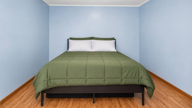 Une pièce avec un lit, des murs de couleur bleu clair et un plancher en bois.