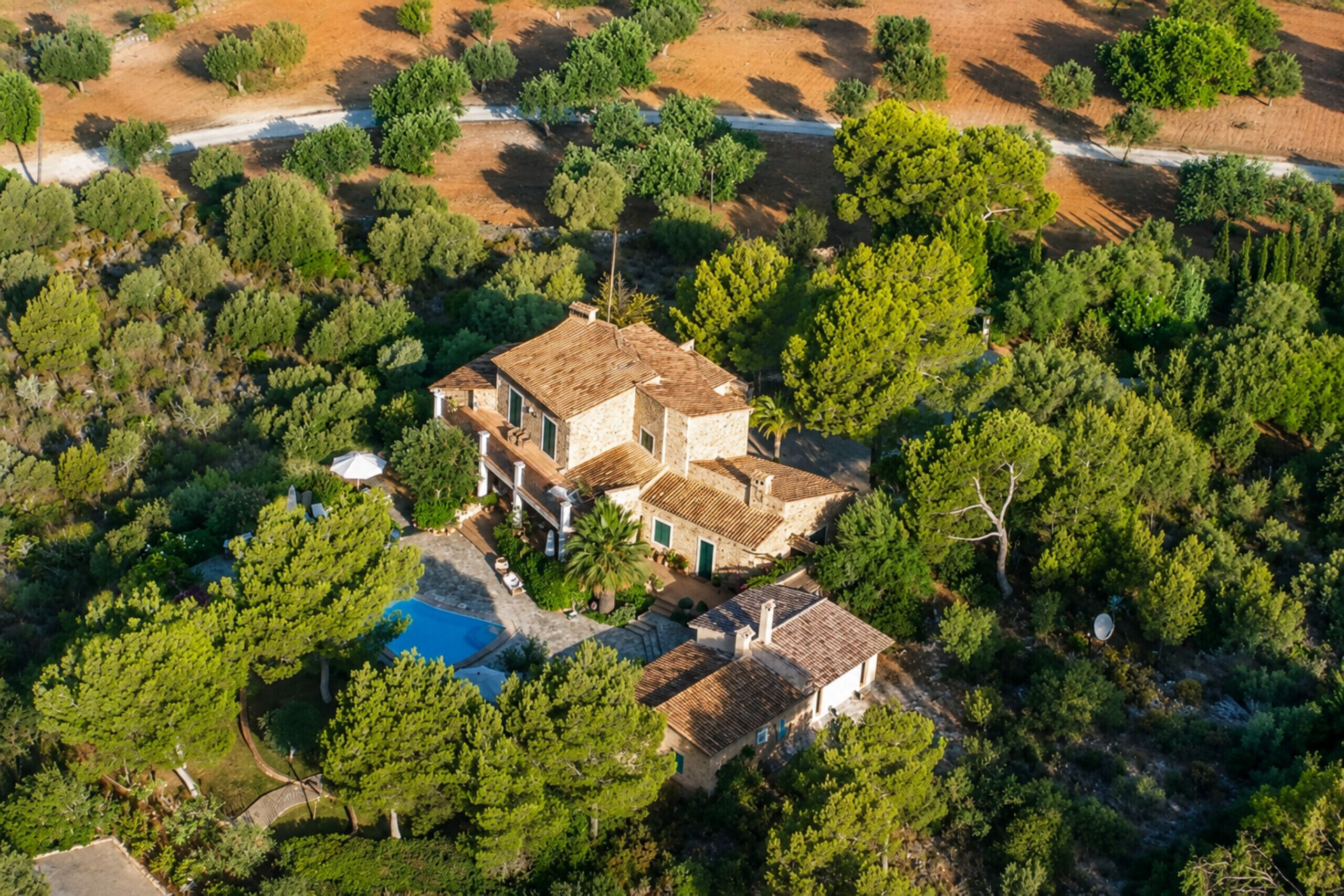 A large estate with multiple buildings, a swimming pool, and lush greenery.