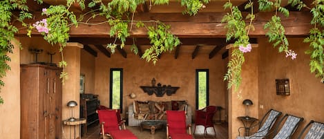 Un área de estar al aire libre con techo, mobiliario de madera y un ambiente rústico.