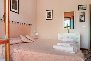Ein Schlafzimmer mit Bett, Kommode, Spiegel und einer Tür.