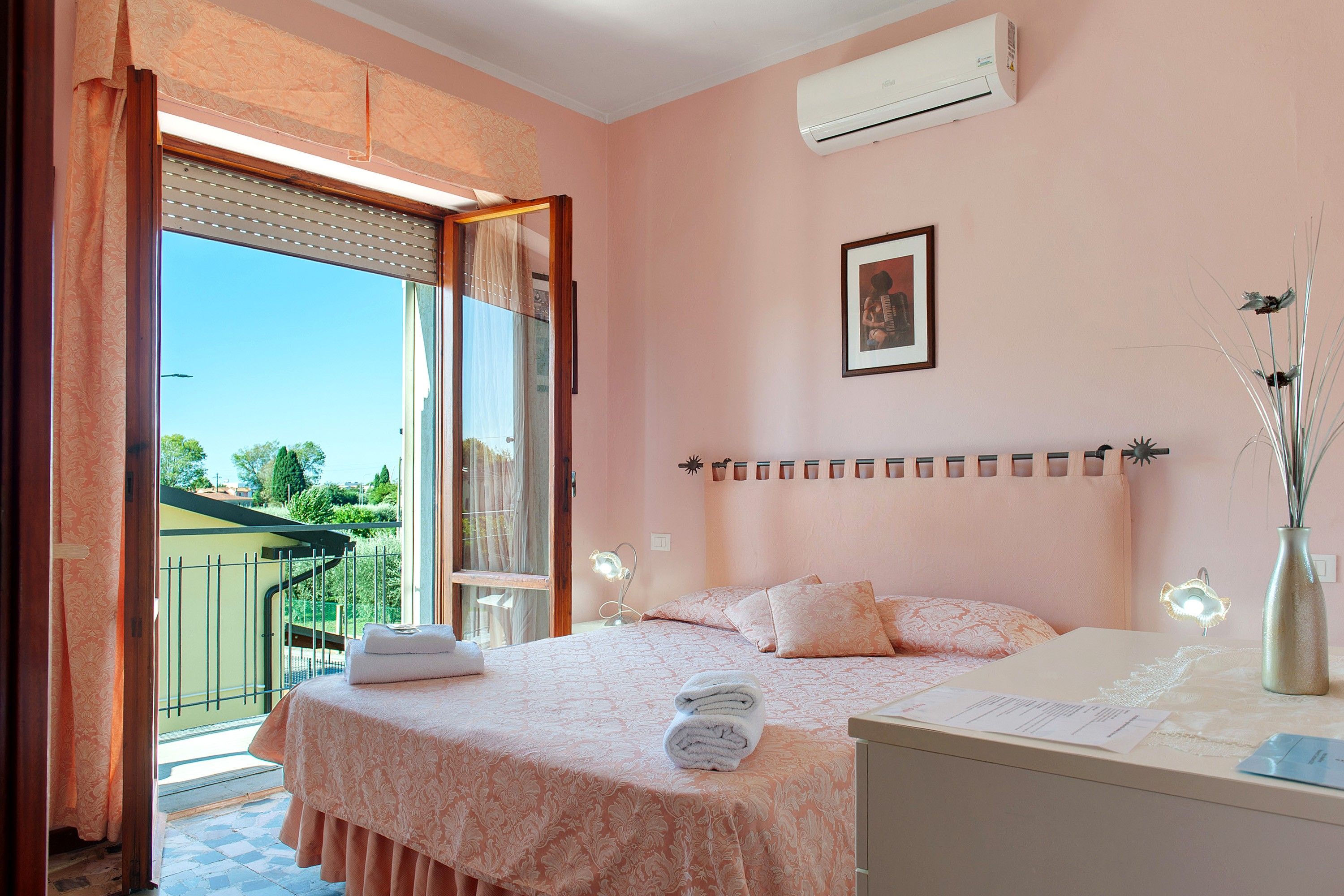 A bedroom with a bed, a nightstand, a mirror, and an air conditioning unit.
