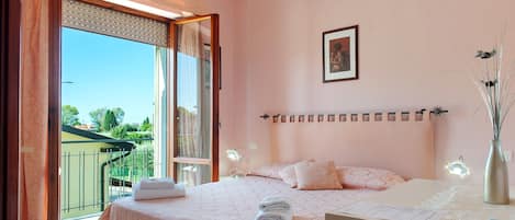 A bedroom with a bed, a nightstand, a mirror, and an air conditioning unit.