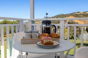 Ein Tisch mit Kaffeekanne, Croissants und Gebäck auf einem Balkon mit Blick.