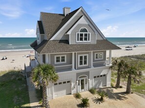 A two-story beachfront house with a garage, a balcony, and a view of the ocean. - Luxury Oceanfront Home w/ Hot tub and Community Pool (North Topsail Beach)