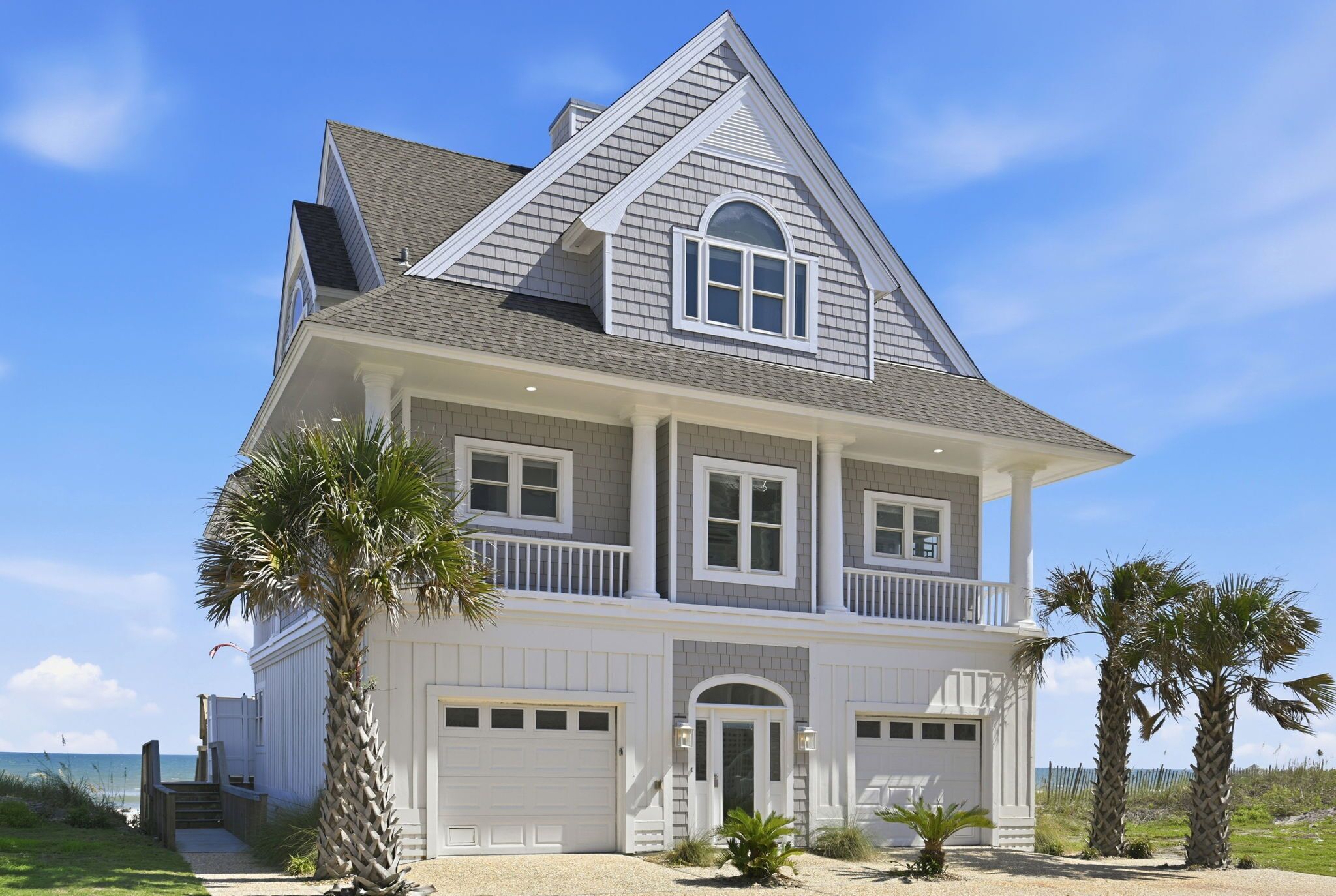 Une maison à deux étages avec un balcon, un garage et une vue sur l’océan.