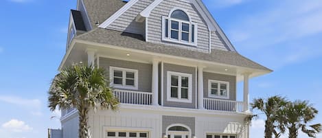 Une maison à deux étages avec un balcon, un garage et une vue sur l’océan.