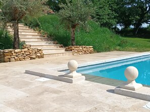 A pool area with stone steps leading to a grassy hill, surrounded by trees. - Charming bed and breakfast with swimming pool in Dordogne (Plazac)