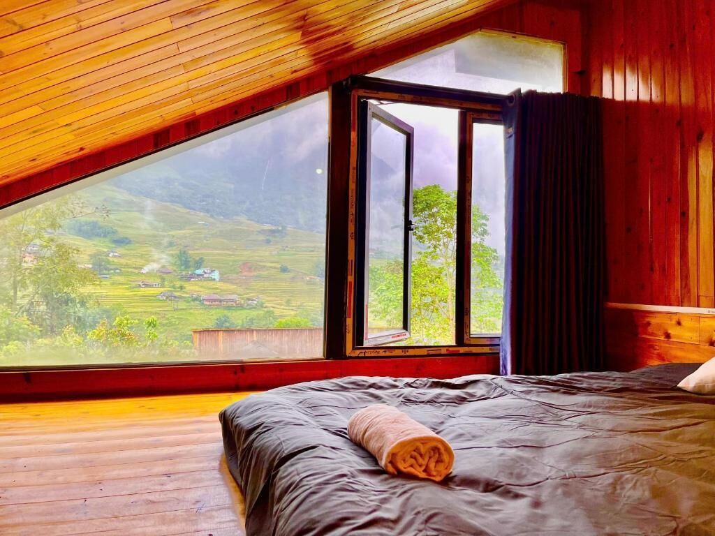 Una habitación con una cama, un ventanal y vistas a un paisaje verde.