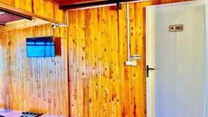 Un interior de madera con una puerta marcada con el número '303' y un televisor fijado a la pared.
