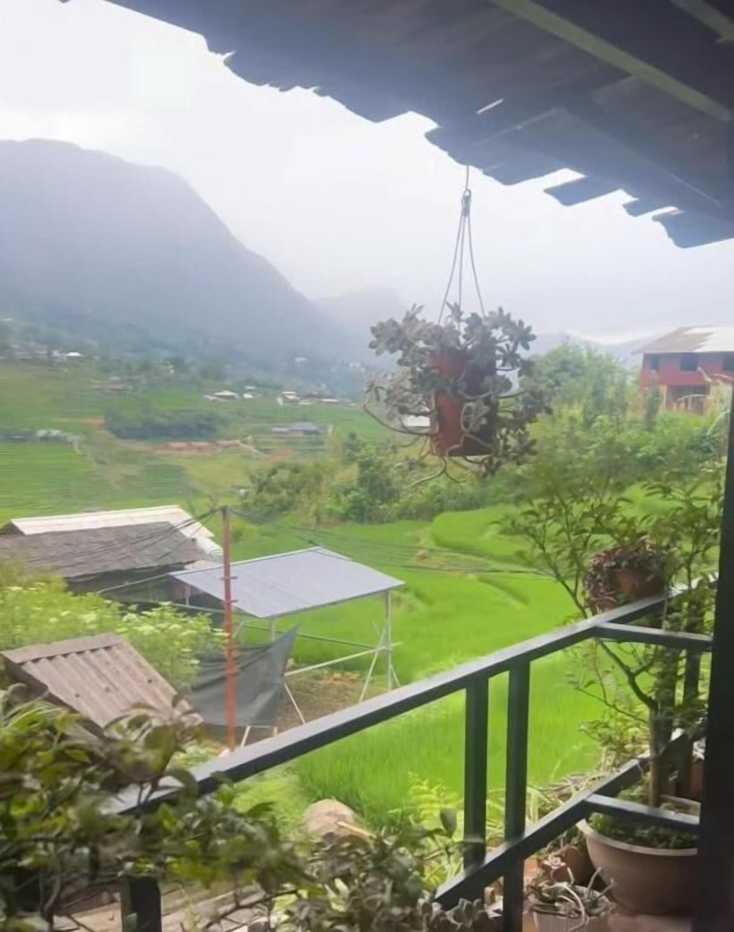 Uma varanda com vista para campos verdes e montanhas ao longe.