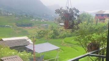 Uma varanda com vista para campos verdes e montanhas ao longe.