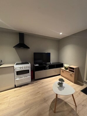 A modern kitchen with a built-in oven, a stove, and a black range hood. - North Nest Studio Apartment (Tromsø)