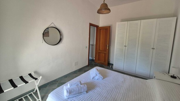 A bedroom with a bed, a hanging light fixture, a round mirror, and a wardrobe. - Apple Cake House - Sweet Silvana (Ischia)