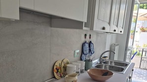 A modern kitchen with a black induction cooktop, white cabinets, and a stainless steel sink. - Apple Cake House - Sweet Silvana (Ischia)