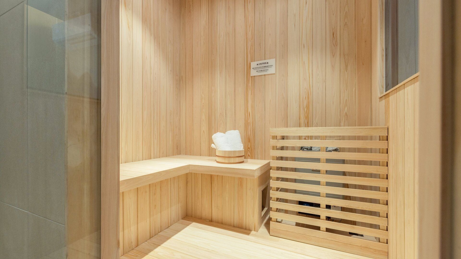 Un sauna en bois avec un banc, un porte-serviettes et un panneau d’avertissement.