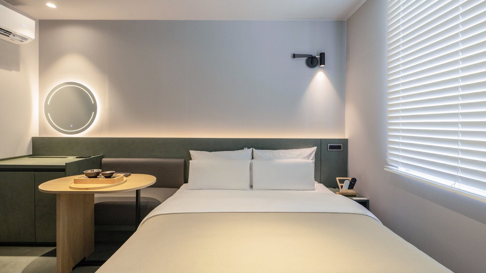 A hotel room with a bed, bedside table, and a wall-mounted light fixture.